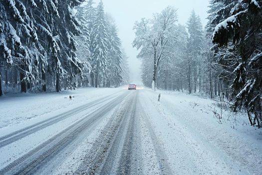 Snowy winter road with car. Dangerous car driving in the mountains in the winter. Concept for transportation, cars and travel.