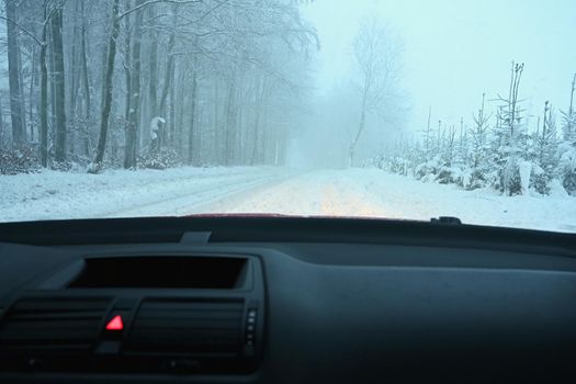 Driving the car in the winter. View from the interior of a car on a snowy road by the eyes of the driver. Concept for driving safety in the winter.