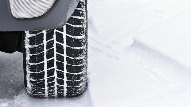 Car in winter. Tire on a snowy road in bad weather.