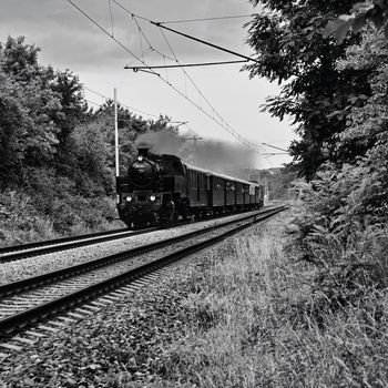 Beautiful old Czech train with steam locomotive. Concept for retro, travel and train travel. Train tracks and a cruise train in the countryside.