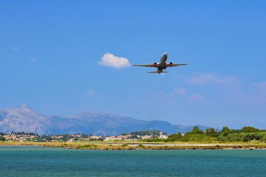 Start of an aircraft at the airport of Corfu - Greece. A short and dangerous airport in the sea with the mountains in the background.