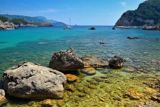Beautiful beach and boats. Clean sea with a bay. Concept for travel, vacation and tourism. Great place for summer holidays and swimming. Paleokastritsa, Corfu island, Greece.