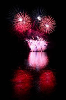 Beautiful colorful fireworks on the water surface. Night scene. Concept for holidays and celebrations.