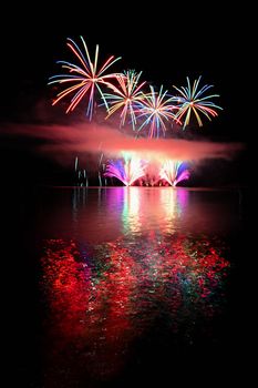 Beautiful colorful fireworks on the water surface. Night scene. Concept for holidays and celebrations.