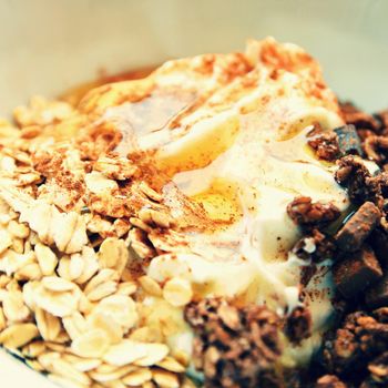 Healthy food - breakfast in a white dish. Muesli, yoghurt, oatmeal with chocolate, honey and cinnamon.