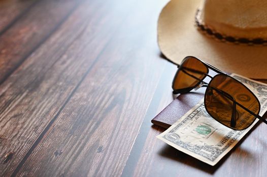 Items for summer vacation: a camera, passport,smartphone, money, hat, sunglasses. Wooden background, top view with Copy space. Beautiful summer concept for travel and summer vacation.