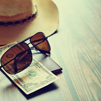 Items for summer vacation: a camera, passport,smartphone, money, hat, sunglasses. Wooden background, top view with Copy space. Beautiful summer concept for travel and summer vacation.