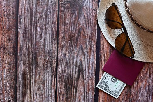 Items for summer vacation: a camera, passport,smartphone, money, hat, sunglasses. Wooden background, top view with Copy space. Beautiful summer concept for travel and summer vacation.