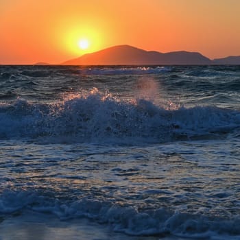 Beautiful sunset with sea and waves. Natural colorful background. Concept for summer and sea vacation. Greece - island of Kos.