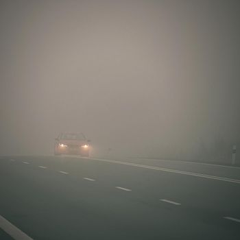 Bad weather driving - foggy hazy country road. Motorway - road traffic. Winter time.