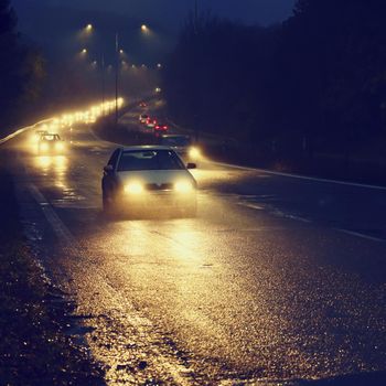 Car on the road in the fog. Autumn landscape - dangerous road traffic in winter season.