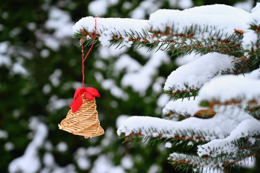 Beautiful natural Christmas decorations made of straw on a snowy Christmas tree. Winter nature colorful outdoor background for the holidays.