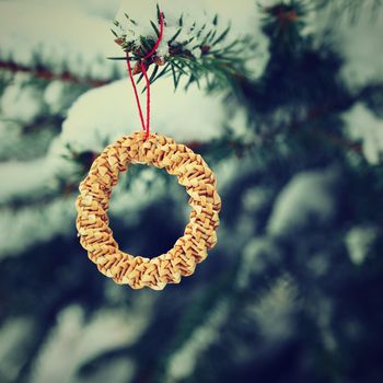 Beautiful natural Christmas decorations made of straw on a snowy Christmas tree. Winter nature colorful outdoor background for the holidays.