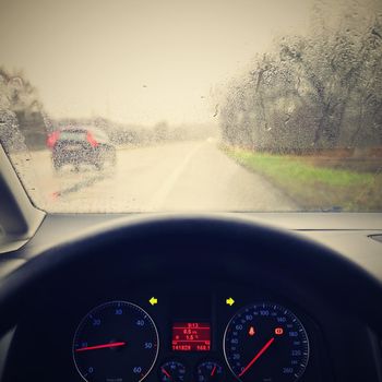 View from the driver - car interior with steering wheel and dashboard. Winter bad rainy weather and dangerous driving on the road.