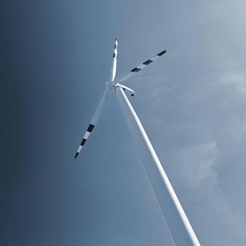 Wind turbine - windmill with blue sky background.
Concept for industry and ecology - green energy.