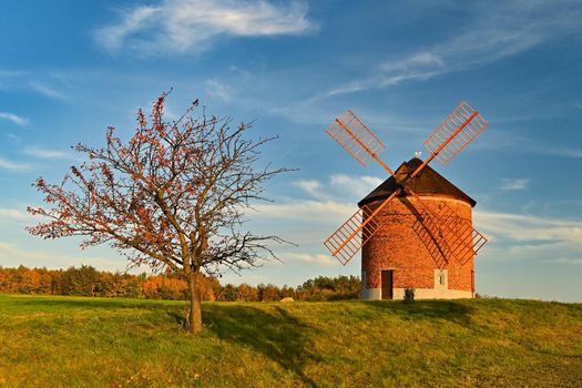 Beautiful autumn landscape with old windmill at sunset and beautiful blue sky with clouds. Colorful nature background on autumn season. Chvalkovice - Czech Republic.