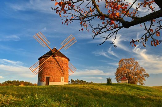 Beautiful autumn landscape with old windmill at sunset and beautiful blue sky with clouds. Colorful nature background on autumn season. Chvalkovice - Czech Republic.