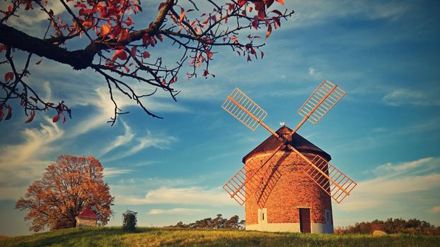 Beautiful autumn landscape with old windmill at sunset and beautiful blue sky with clouds. Colorful nature background on autumn season. Chvalkovice - Czech Republic.
