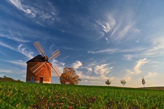 Beautiful autumn landscape with old windmill at sunset and beautiful blue sky with clouds. Colorful nature background on autumn season. Chvalkovice - Czech Republic.