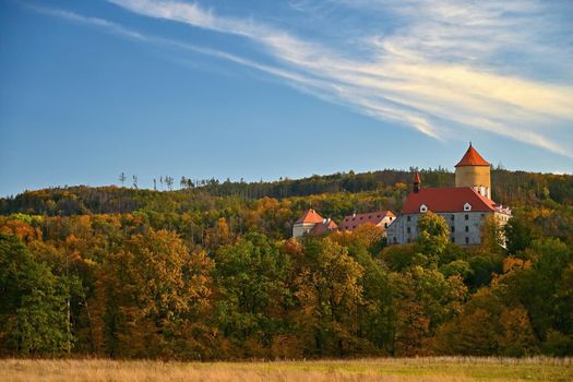 Beautiful autumn landscape with old castle Veveri at sunset and beautiful blue sky with clouds. Colorful nature background on autumn season. Brno - Czech Republic.