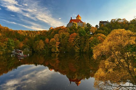 Beautiful autumn landscape with old castle Veveri at sunset and beautiful blue sky with clouds. Colorful nature background on autumn season. Brno - Czech Republic.