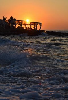 Beautiful summer sunset by the sea. Amazing scenery on the beach with waves and reflection of the sun. Background for holiday and vacation travel. Greece Crete Island.
