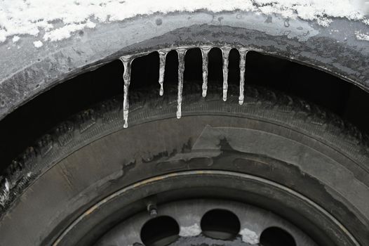 Frozen car with a tire. Icicles on the car. Concept for winter and dangerous traffic of cars on the road.
