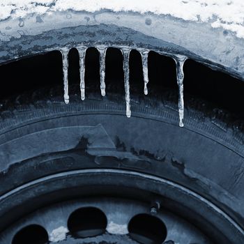 Frozen car with a tire. Icicles on the car. Concept for winter and dangerous traffic of cars on the road.