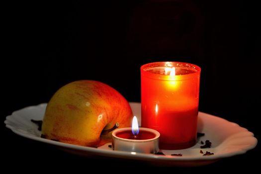 Candle decorated with red apple. Christmas decoration Black clean background with copy space.