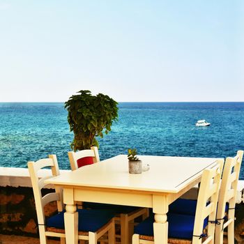 A covered table in a Greek tavern and a sea. Summer background for travel and holidays.
