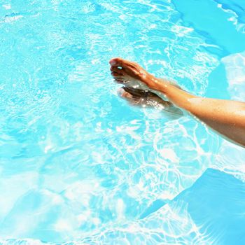 Legs in the pool with clean water in hot sunny day. Summer background for traveling and vacation. Holiday idyllic.