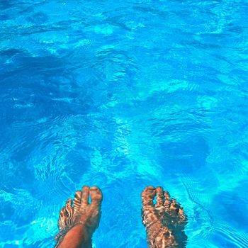 Legs in the pool with clean water. Summer background for traveling.