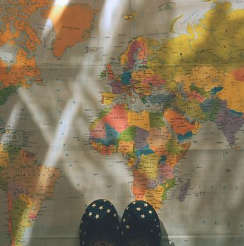 Beautiful concept for summer travel. Small children's shoes on the world map. Planning a summer vacation and holidays.