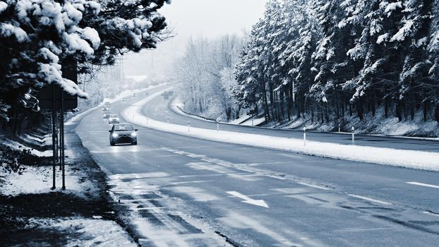 Cars on winter road with snow. Dangerous automobile traffic in bad weather.