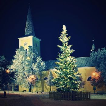 Beautiful night winter photo Christmas tree with church and snow.