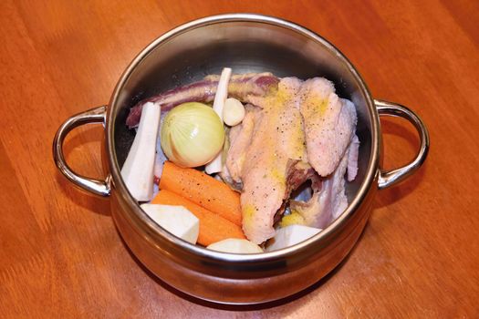 Preparing homemade chicken soup - broth. Pot on the stove in the kitchen with ingredients for cooking.