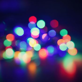 Christmas blurred lights on black background with copy space. Abstract colorful reflections of bulbs on a Christmas tree.