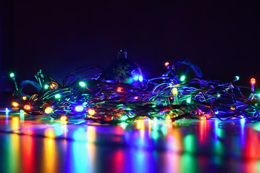 Christmas blurred lights on black background with copy space. Abstract colorful reflections of bulbs on a Christmas tree.