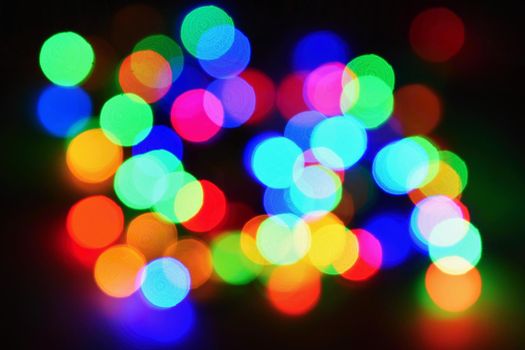 Christmas lights on black background with copy space. Colored reflecting surface.