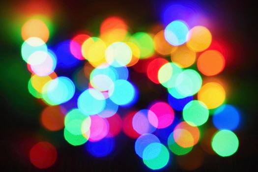 Christmas lights on black background with copy space. Colored reflecting surface.