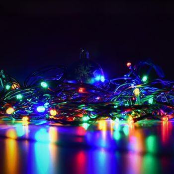 Christmas lights on black background with copy space. Colored reflecting surface.