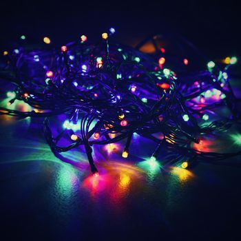 Christmas lights on black background with copy space. Colored reflecting surface.