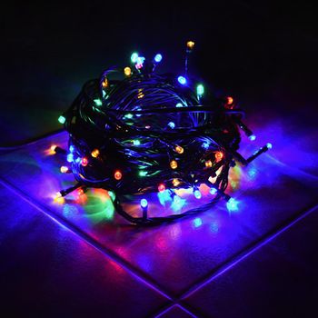 Christmas lights on black background with copy space. Colored reflecting surface.