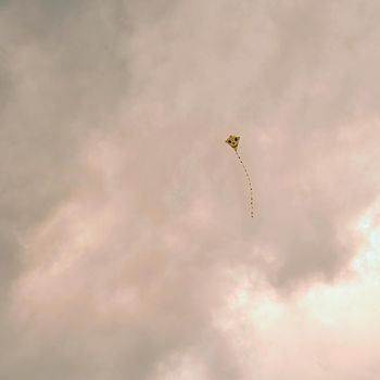 Kite flying in the beautiful autumn windy day. Blue sky background with sun and clouds.