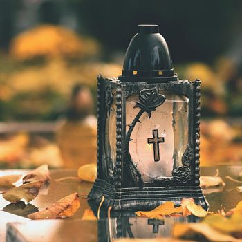 Beautiful autumn concept to the cemetery and Halloween. Candle in a lantern on the grave. Background for Halloween.