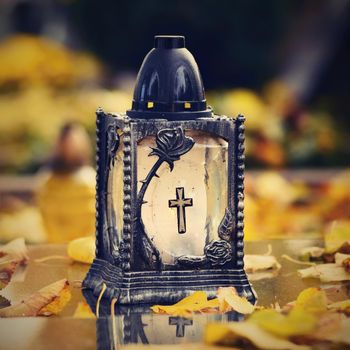 Beautiful autumn concept to the cemetery and Halloween. Candle in a lantern on the grave. Background for Halloween.