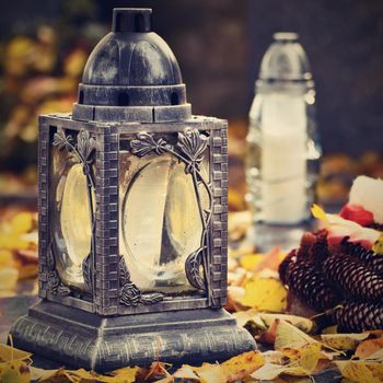 Beautiful autumn concept to the cemetery and Halloween. Candle in a lantern on the grave. Background for Halloween.