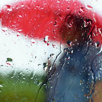 A man under an umbrella in the rain. Drops with a blurred background.