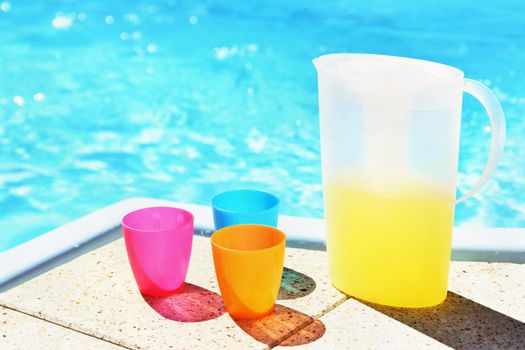 Drink in a teapot with cups at the pool. Drinking water in the hot summer.