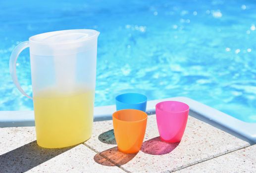 Drink in a teapot with cups at the pool. Drinking water in the hot summer.